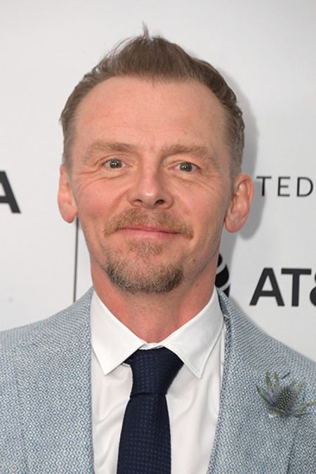 Simon Pegg in a grey suit poses for a picture.